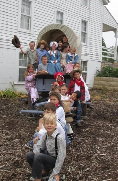 School kids posed by the covered wagon while on a school tour